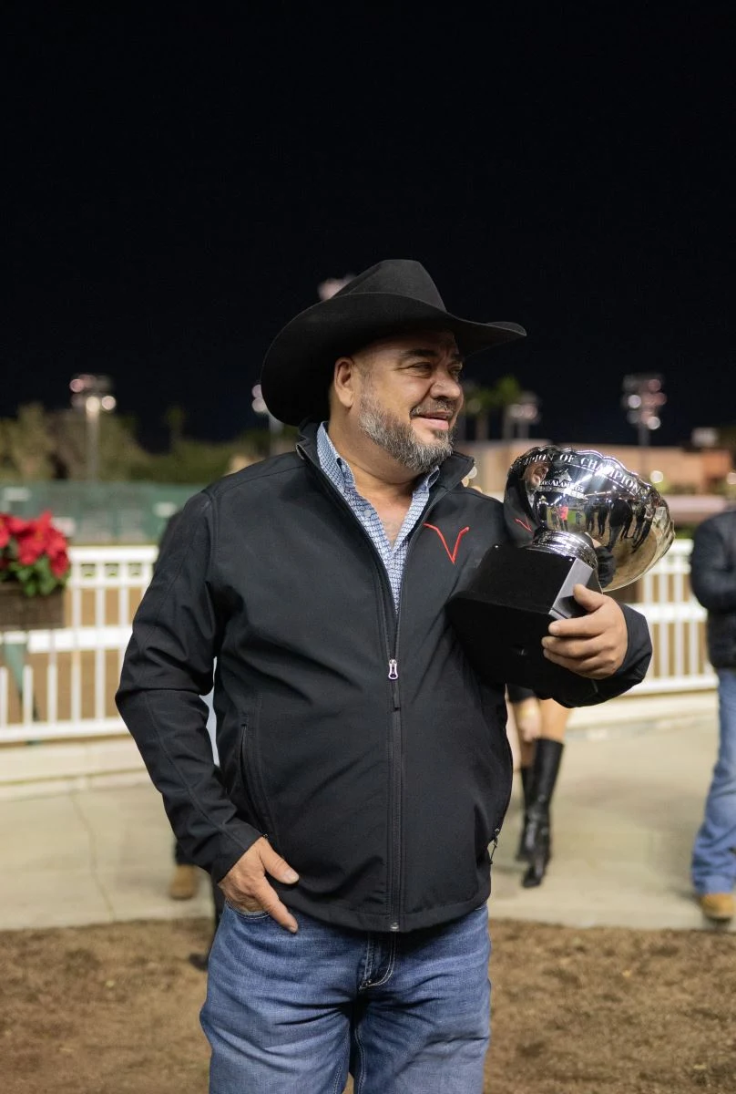 Owner Sammy Valeriano holding the Champion of Champions trophy after Flash Bak's 2023 victory
