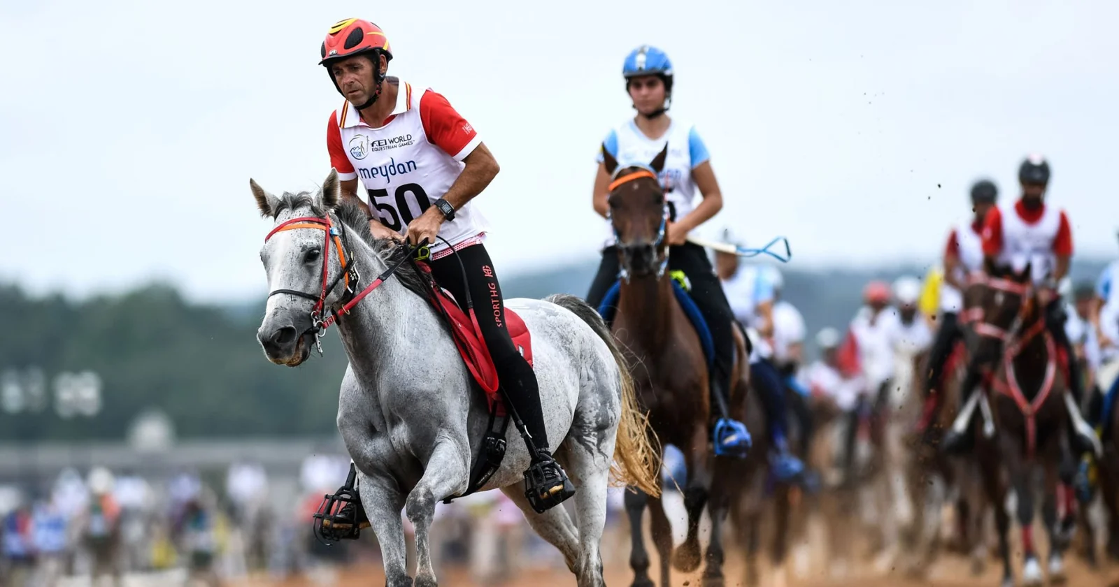 Endurance riders wearing numbered bibs on horses outdoors