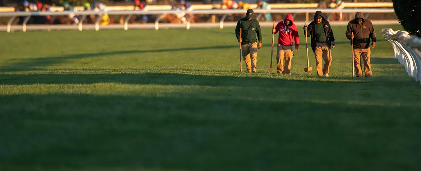 Keeneland grounds crew working on the turf course beside the rail