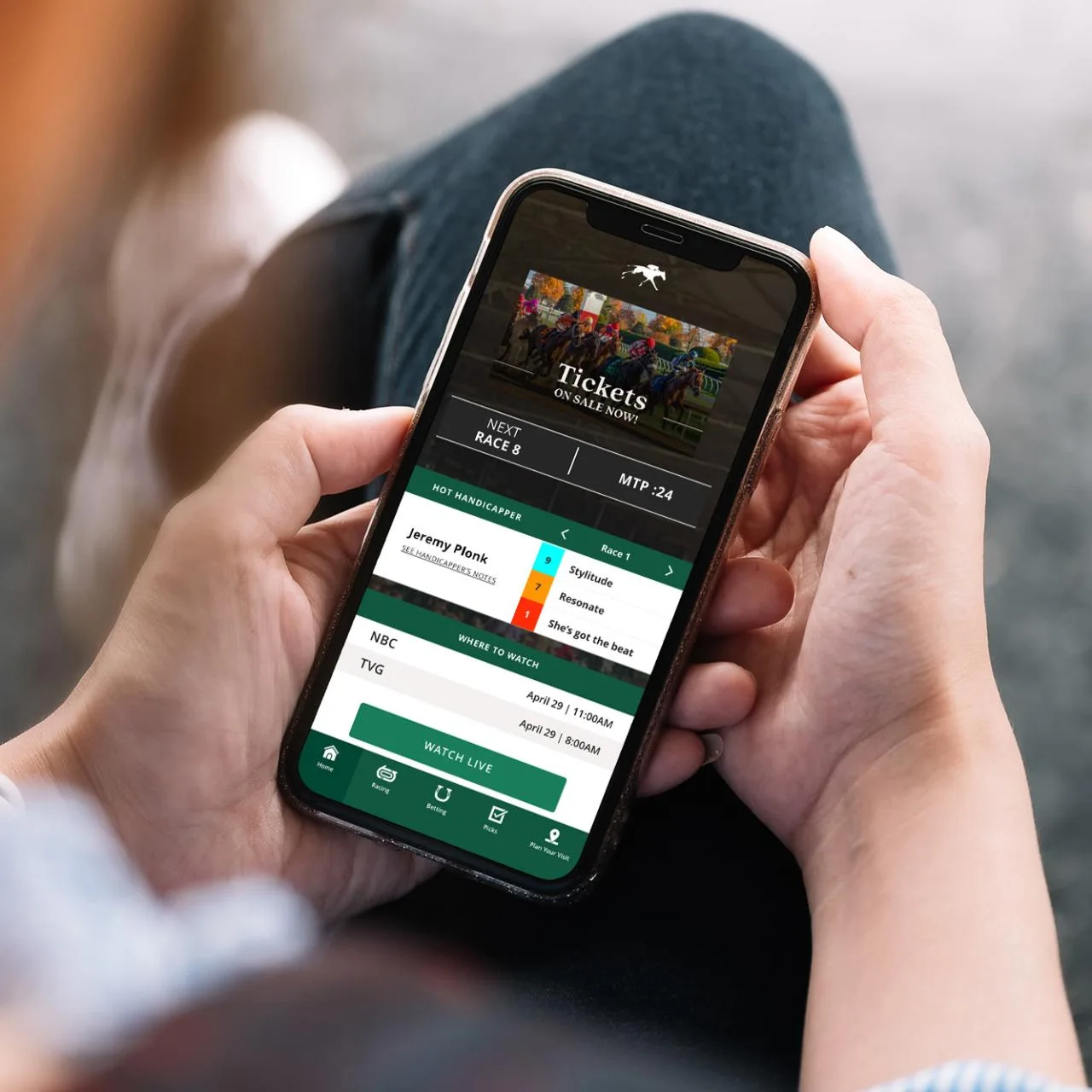 Hands holding a phone displaying Keeneland’s Race Day app in an official archive photograph